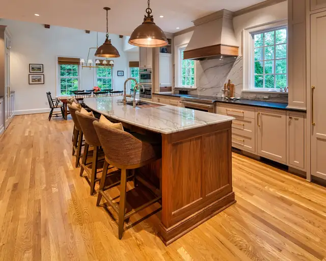 Kitchen by Custom Kitchens with a walnut island, copper pendant lights, a plaster range hood and wide plank oak floors