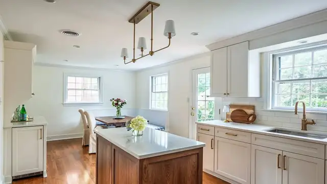 Charming Richmond kitchen behind Monument with white cabinets, a walnut island, brass pendants and hardwood floors