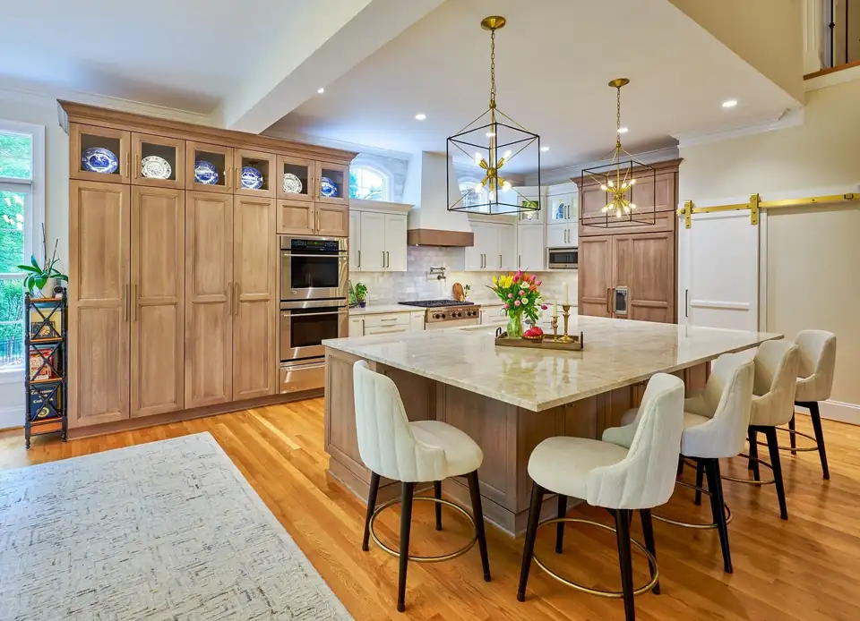 Kitchen remodeling Richmond VA project: Tarrington kitchen with natural wood cabinetry, a stone-topped island, white swivel stools and lantern pendants