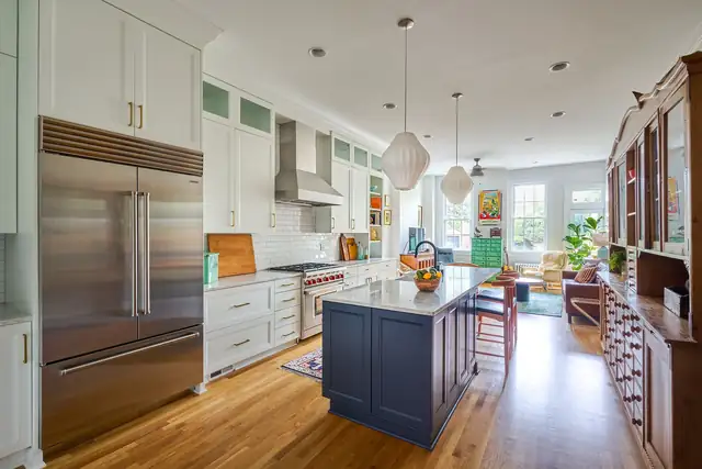Old Meets New on Hanover kitchen in Richmond with a navy island, white cabinetry, stainless built-in refrigerator and long open floor plan